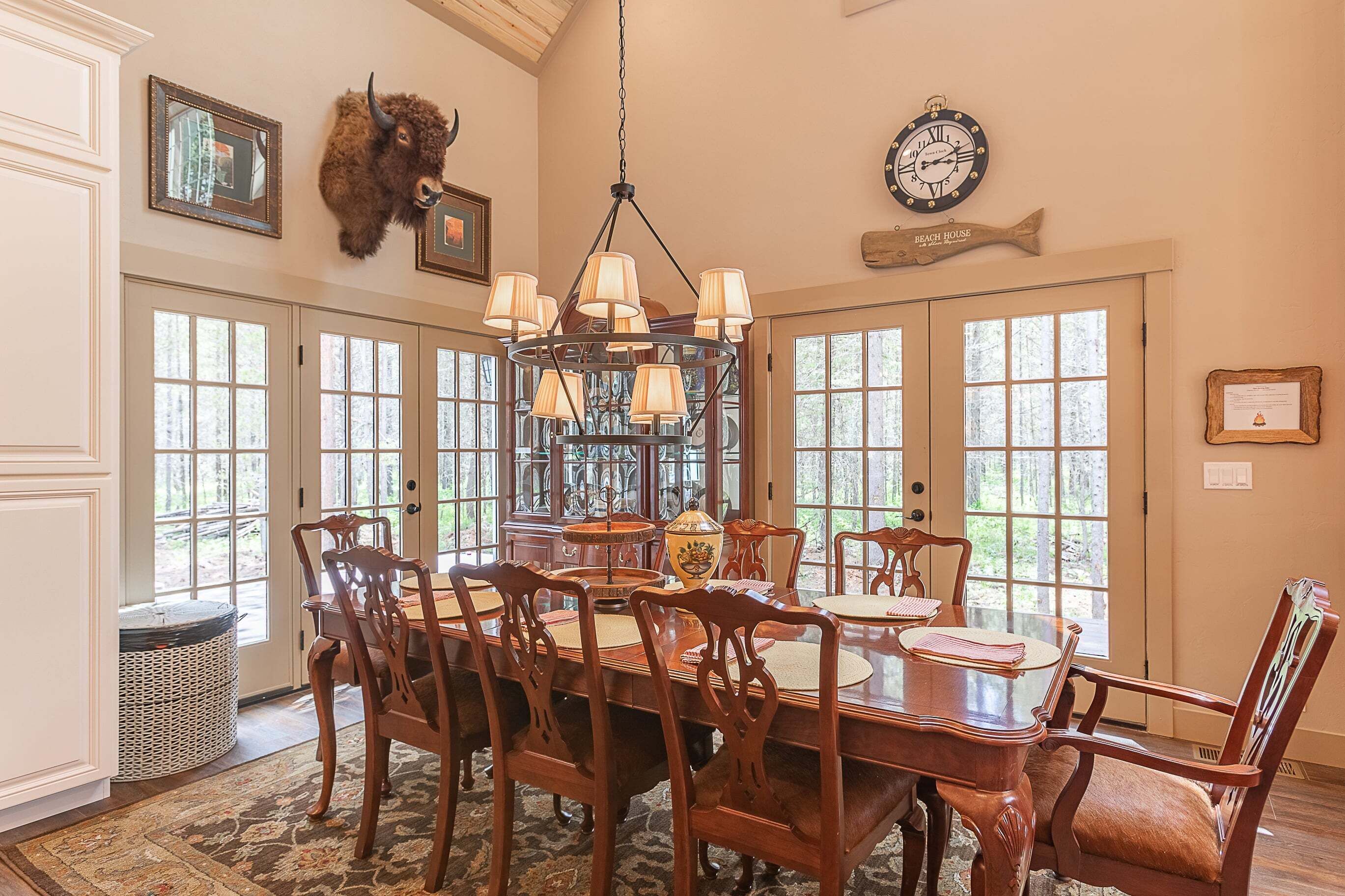 A dining area with a chandelier, wooden chairs, and a table.