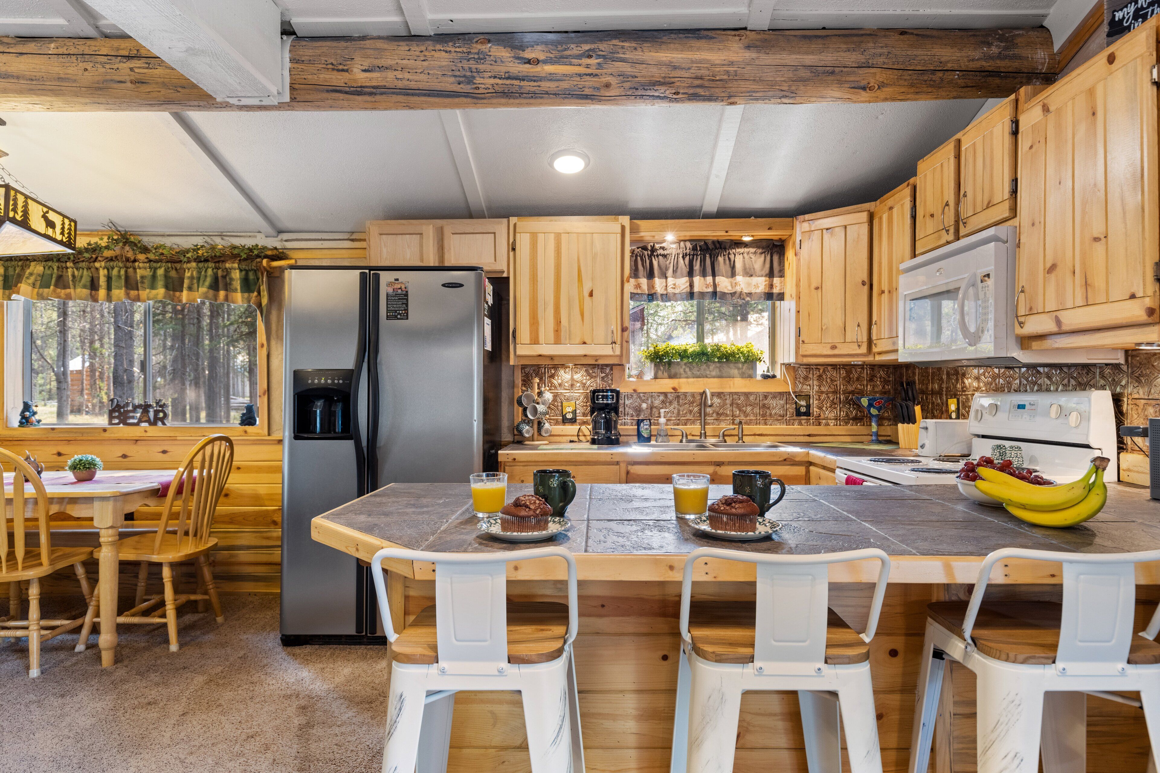 A kitchen with wooden cabinets, a refrigerator, a microwave, a coffee maker, and a dining area with a table and chairs.