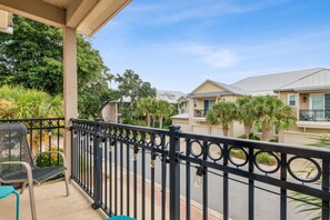 A balcony with a black metal railing, a chair, and a table. - 905 Summerwoods Cir (Fernandina Beach)