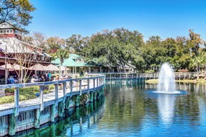A waterfront area with a bridge, a fountain, and buildings with outdoor seating. - 1876 Turtle Dunes Amelia Island Plantation (Fernandina Beach)