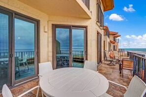 A balcony with a table and chairs, a view of the ocean, and a building with balconies. - 1876 Turtle Dunes Amelia Island Plantation (Fernandina Beach)
