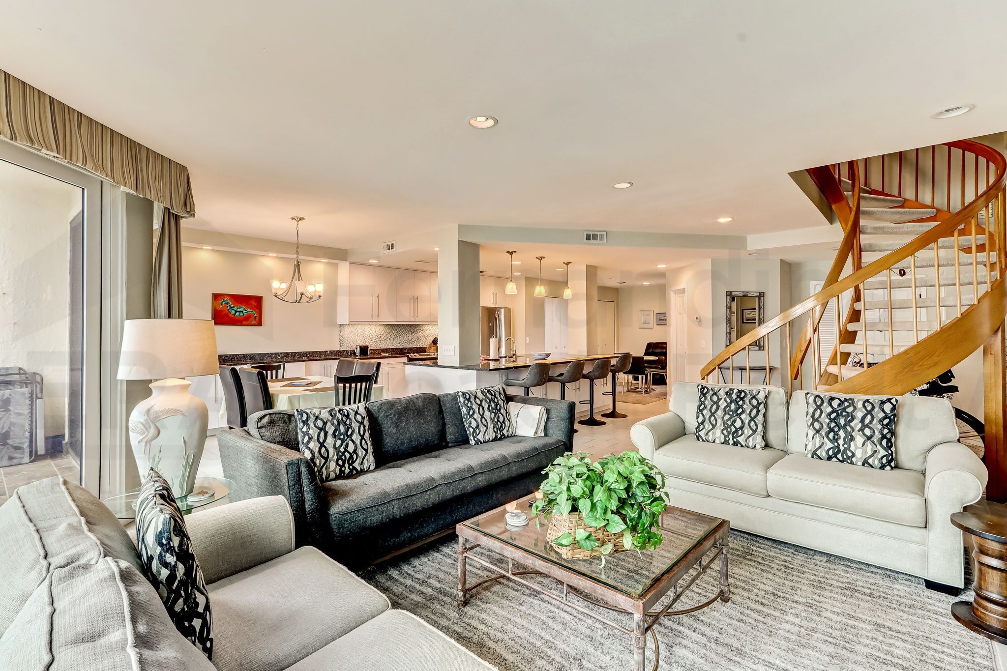 A modern living room with a sofa set, a coffee table, and a staircase.