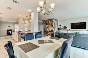A modern living room with a dining area, a staircase, and a TV. - 1876 Turtle Dunes Amelia Island Plantation (Fernandina Beach)