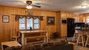 A wooden interior with a dining area, kitchen, and seating. - Remington Reload (Island Park)