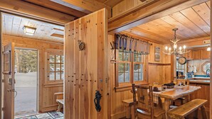 A wooden cabin interior with a dining area, wooden walls, and a large window. - Double Loop (Island Park)