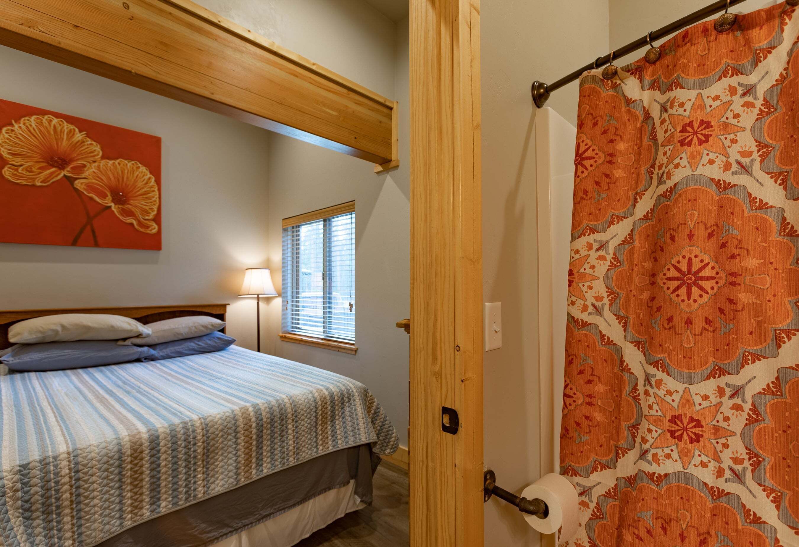 A bedroom with a bed, a window, a door, and a shower curtain.