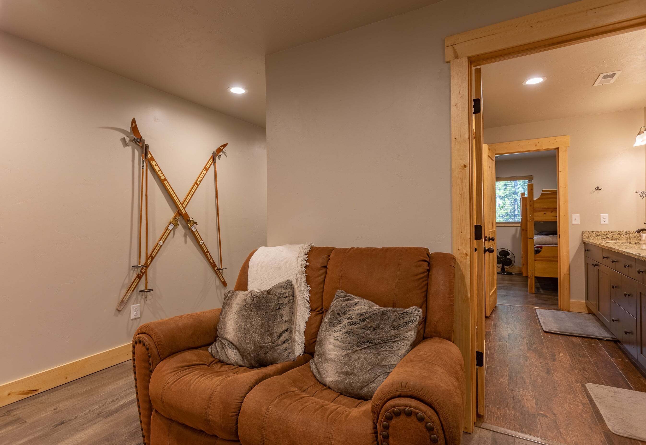 A living room with a brown sofa, two gray pillows, and a white throw blanket.