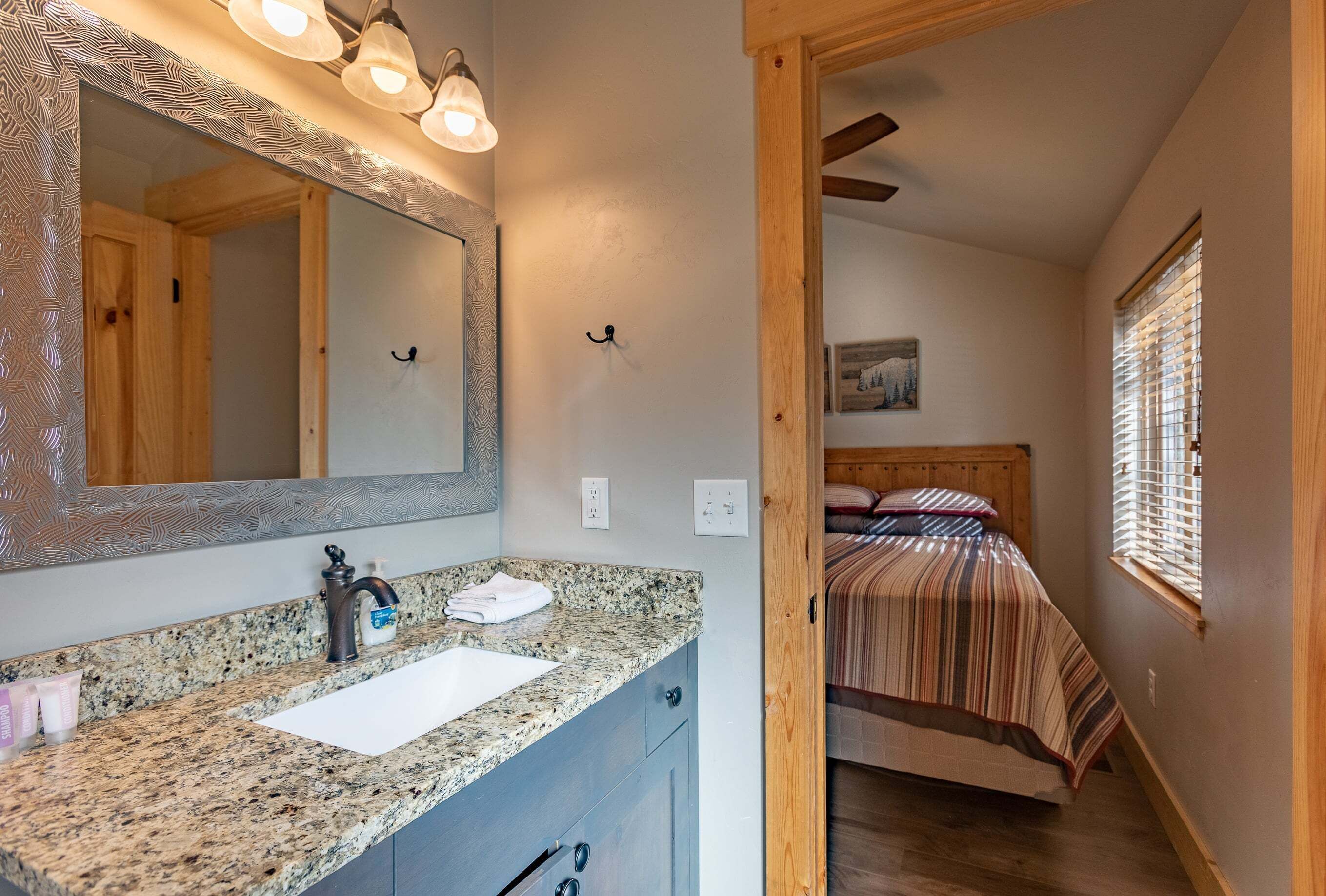 Une salle de bain avec un comptoir en granit, un lavabo, un miroir et un porte-serviettes.