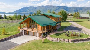 Une cabane en rondins avec un toit végétalisé, une véranda et une vue sur les montagnes et un lac.