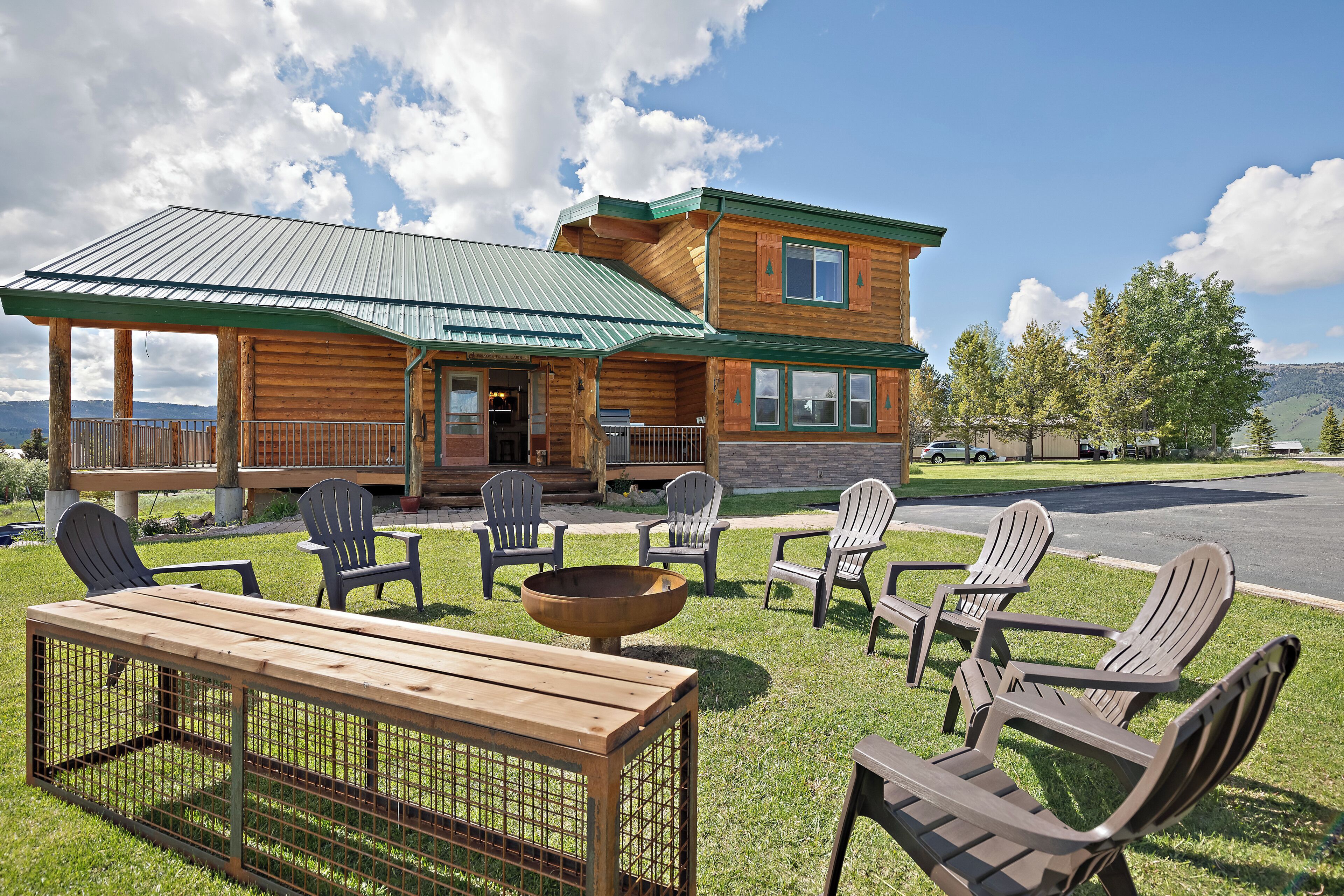A log cabin with a porch, outdoor seating, and a fire pit.