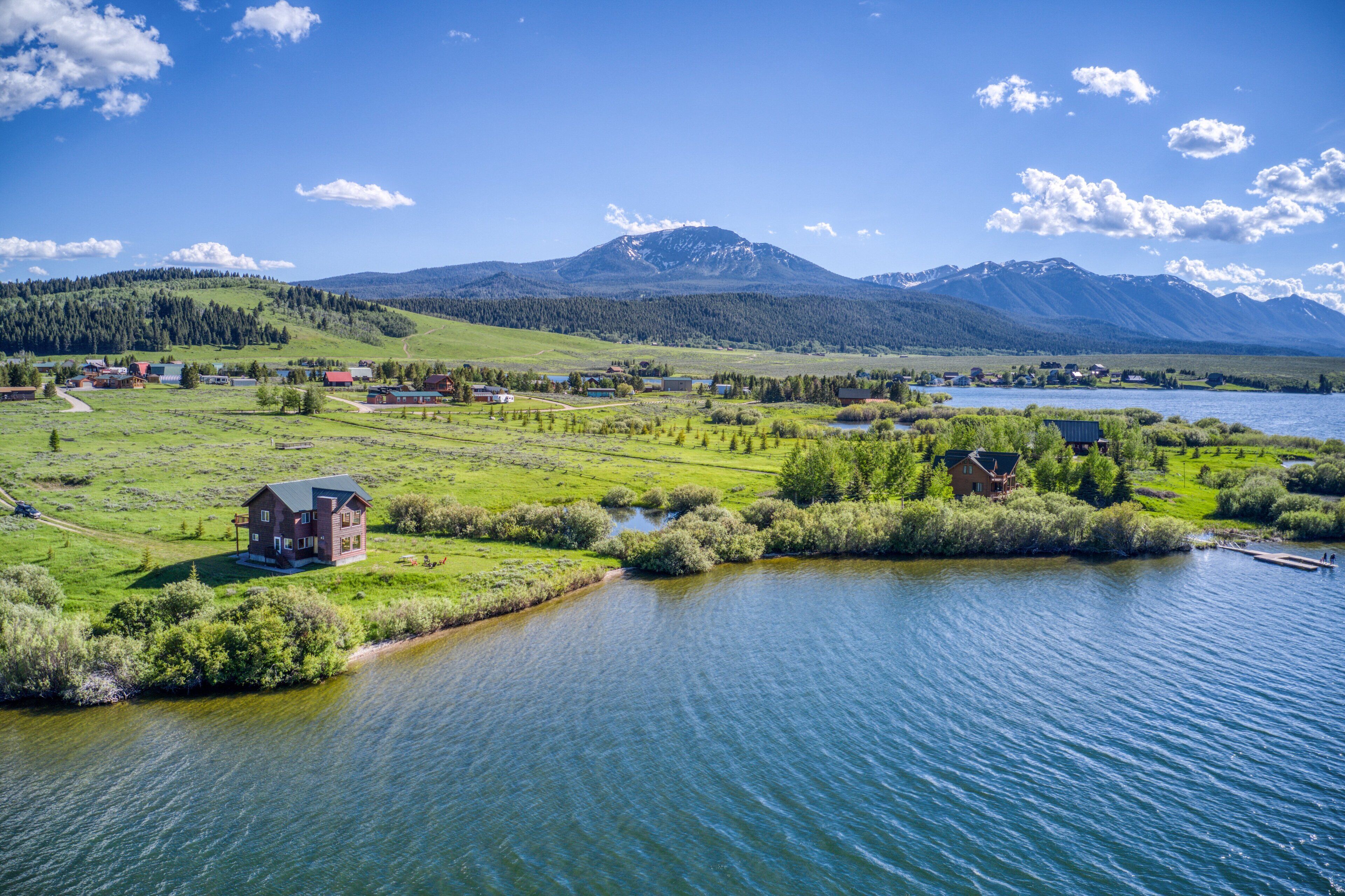 A lakeside property with a large house, a dock, and a view of mountains.