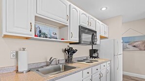 A modern kitchen with white cabinets, stainless steel appliances, and a granite countertop. - Torch Lake Vista A Ga Ming Golf Retreat 741 Unit 9B (Kewadin)