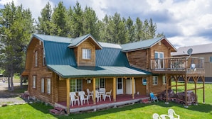 A log cabin with a porch, outdoor seating, and a covered deck area. - Grand View Retreat (Island Park)