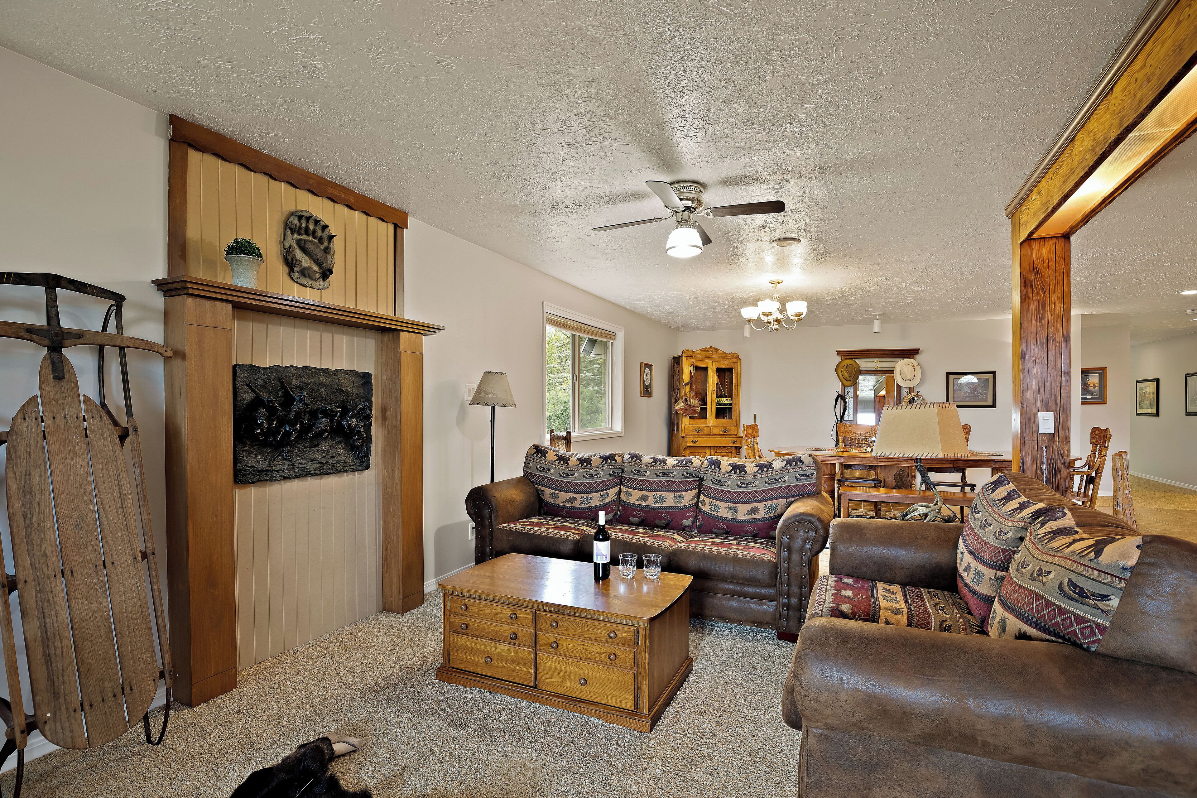 A cozy living room with a wooden coffee table, leather sofas, a wooden cabinet, and a ceiling fan.