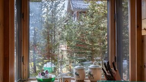 Ein Holztisch mit Geschirr und Blick aus dem Fenster auf ein bewaldetes Gebiet.