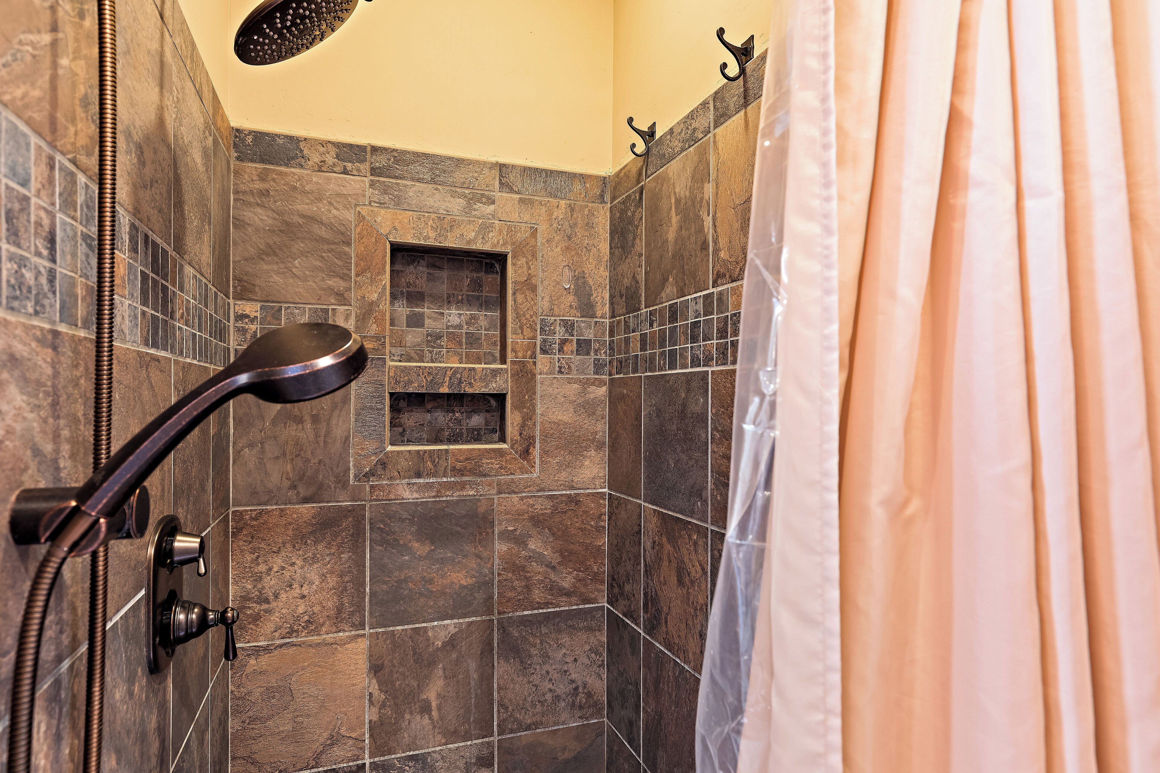 A shower area with a handheld showerhead and a wall-mounted control.
