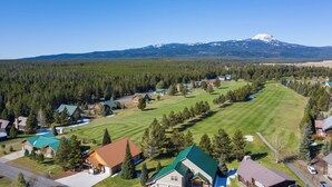 A residential area with houses, a green field, and a mountain with snow in the background. - Huckleberry Hollow (Island Park)