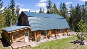 Eine Blockhütte mit Metalldach, einer Holzterrasse und einem Steinfundament.