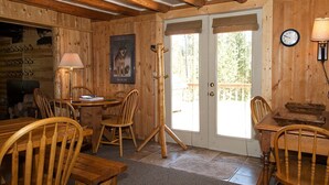 Ein Holzinterieur mit einer Essecke, Stühlen, einem Tisch, einer Tür und einer Wanduhr.