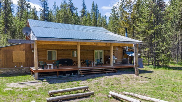 Eine Holzhütte mit Veranda, Sitzgelegenheiten im Freien und einem Feuerkorb.