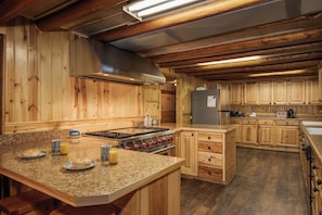 A spacious kitchen with wooden cabinets, granite countertops, and a central island. - Grey Wolf Retreat (Island Park)