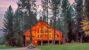 A log cabin with a balcony, surrounded by tall trees. - Lumberjack Lodge (Island Park)