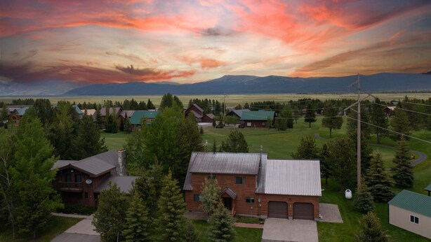 A rural landscape with houses, a mountain range, and a cloudy sky. - Deer View (Island Park)