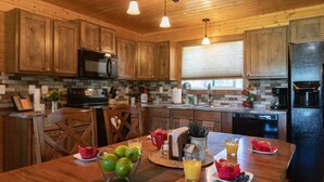 A wooden kitchen with a central island, a microwave, and a refrigerator. - Deer View (Island Park)