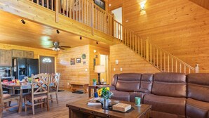A wooden interior with a dining area, a sofa, and a staircase. - Deer View (Island Park)