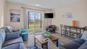Un salon comprenant un canapé, une table basse, un téléviseur et un coin repas avec des chaises et une table.