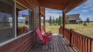 Eine Holzterrasse mit Schaukelstühlen und Blick auf eine Berglandschaft.