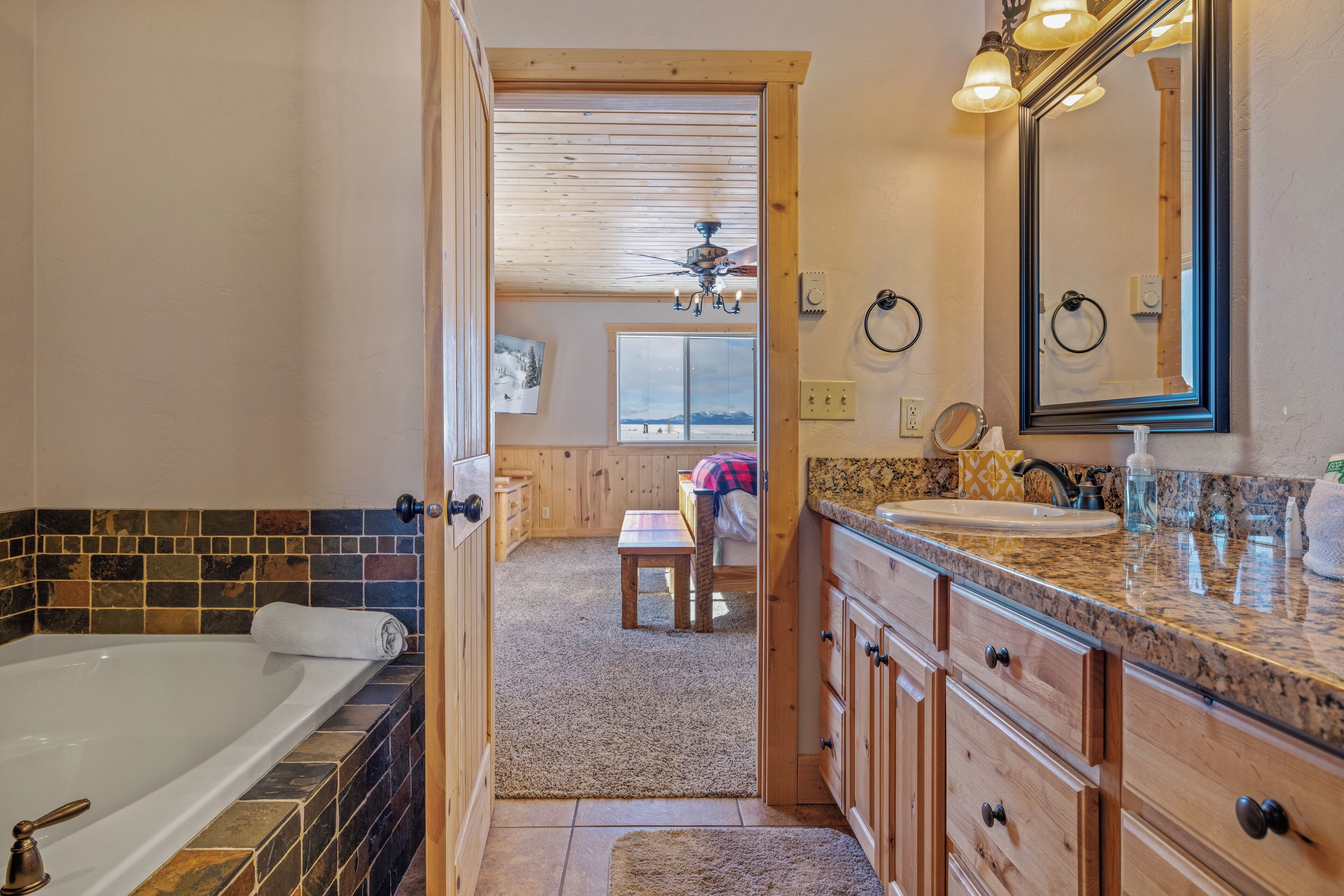A bathroom with a bathtub, vanity, and a large mirror.