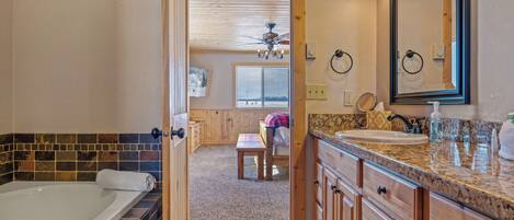 A bathroom with a bathtub, vanity, and a large mirror.