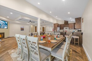 A spacious dining area with a wooden table set for six, surrounded by white chairs with cushioned seats. - Kings Retreat (Island Park)