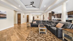 Ein geräumiges Wohnzimmer mit einer großen Eckcouch, einem Couchtisch und einem Deckenventilator.