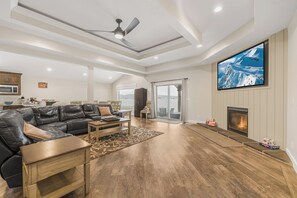A spacious living room with a fireplace, a large TV, and a ceiling fan. - Kings Retreat (Island Park)