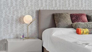 A neatly made bed with a white quilt, a bedside lamp, and a nightstand with a candle and a book. - Coastal Enclave Key Biscayne Oceanview w Pool (Key Biscayne)