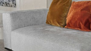 A grey sofa with two cushions, one brown and one orange, in a modern room with a light-colored wall and a piece of abstract art. - Coastal Enclave Key Biscayne Oceanview w Pool (Key Biscayne)