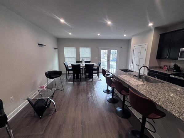 A modern kitchen with a central island, bar stools, and a dining area with chairs.