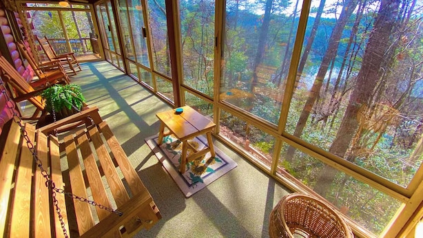 A sunlit room with large windows, wooden furniture, and a view of a forest. - Moonlit Mountain: A peaceful escape to reconnect, unwind, and breathe deep (Ellijay)