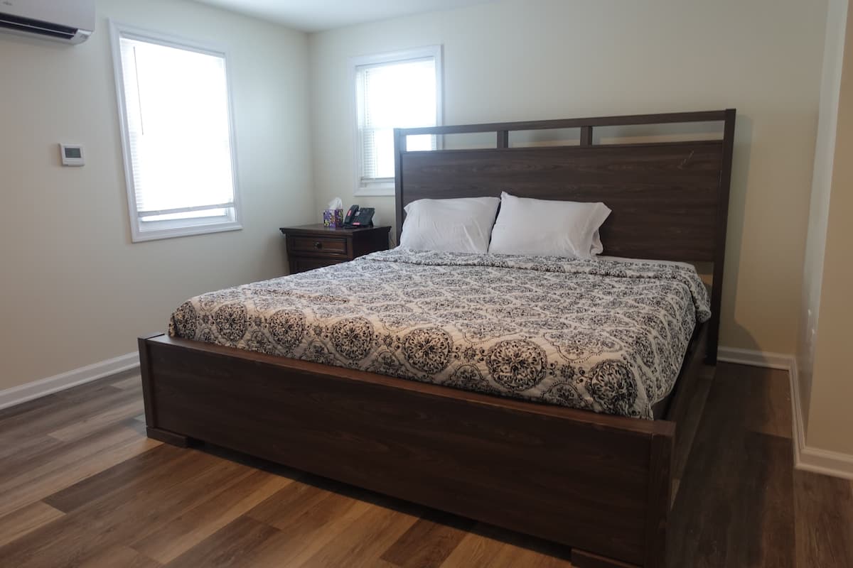 A bedroom with a wooden bed, two bedside tables, a nightstand, and a window.