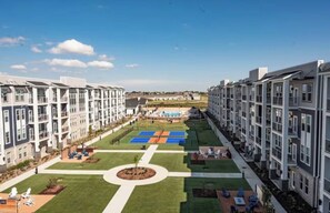 Un complex residencial amb diversos edificis d'apartaments, un pati central amb una pista de tennis i zones d'estar a l'aire lliure.