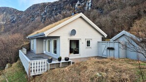 Een huis met een schuin dak, een schotels en een terras met bloempotten.