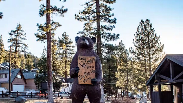 Une statue d’ours tenant une pancarte sur laquelle on peut lire : « Louis vous souhaite la bienvenue à Big Bear Lake, en Californie. »