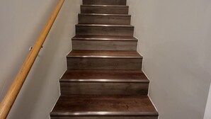 Een houten trap met een leuning, die uitkomt op een plateau.