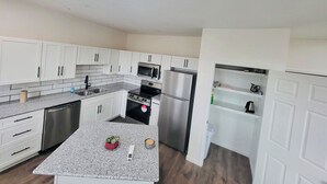 Een moderne keuken met witte kasten, roestvrijstalen apparatuur en een granieten aanrecht.