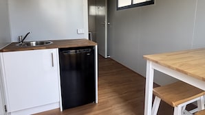 A compact kitchen with a dishwasher, a wooden countertop, and a white cabinet.