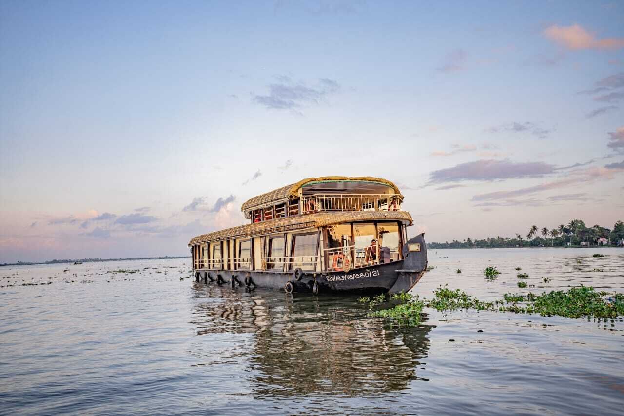 A houseboat with a covered upper deck, multiple windows, and a flat roof.