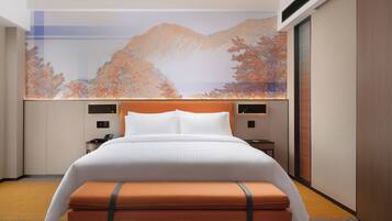 Habitación de hotel con una cama grande, una mesita de noche, un televisor montado en la pared y un amplio ventanal con vista a la montaña.