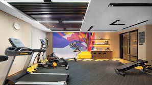 A gym with treadmills, elliptical machines, and a weight bench.